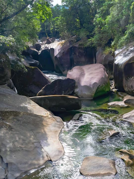 Babinda Boulders, smooth rocks and flowing creek surrounded by lush forest in Queensland, Australia.