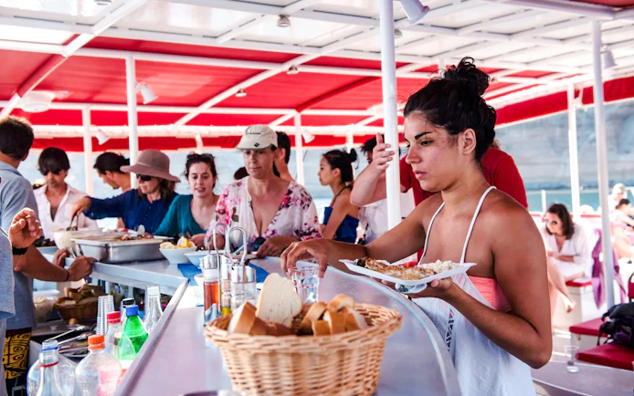 Guests enjoying snacks on the Catamaran Red Cruise with a view of the sea.