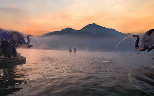 Couple enjoying hot spring at Toya Devasya, Kintamani, Bali, with mountain view.