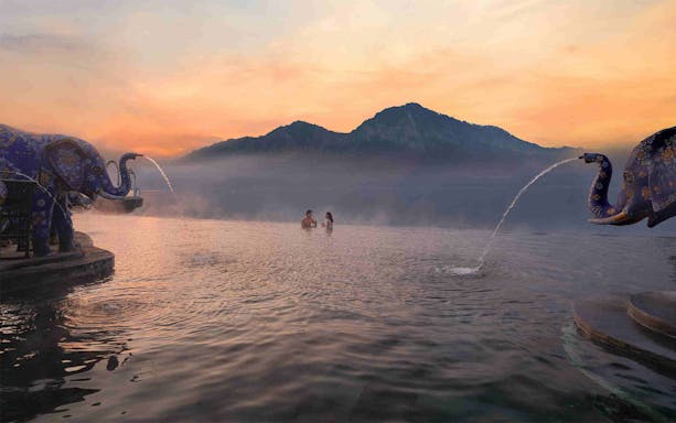 Couple enjoying hot spring at Toya Devasya, Kintamani, Bali, with mountain view.
