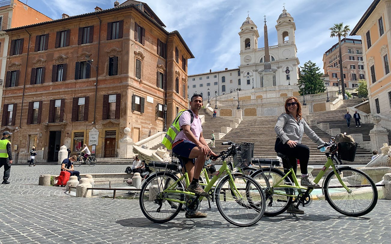 Cyclists at the Spanish Steps in Rome, Italy, with Trinità dei Monti in the background.