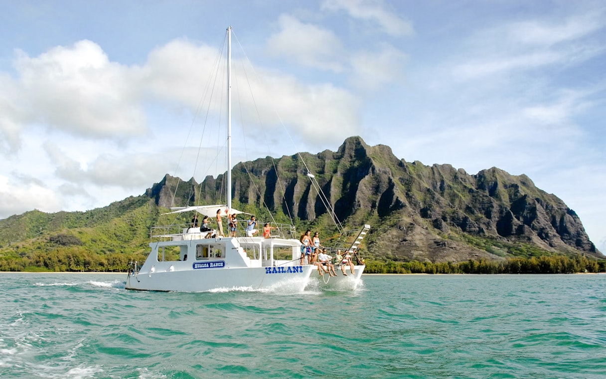 Catamaran sailing near Kualoa Ranch mountains, Ocean Voyage Adventure, Hawaii.