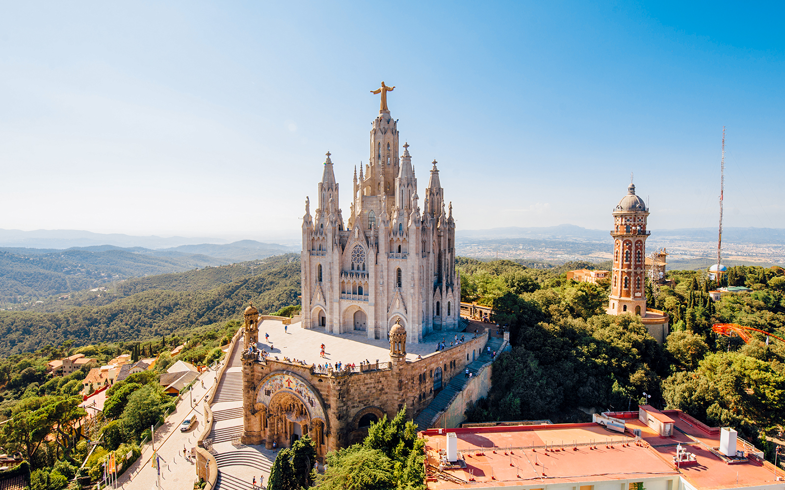 Tibidabo church with Christ statue on mountain in Barcelona, overlooking city and landscape.