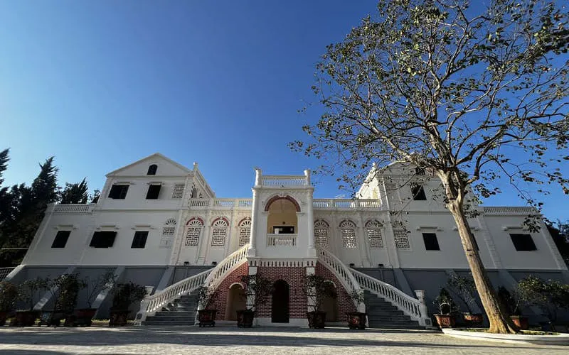 White colonial-style building with arched windows at Bac Ha Market, Vietnam.