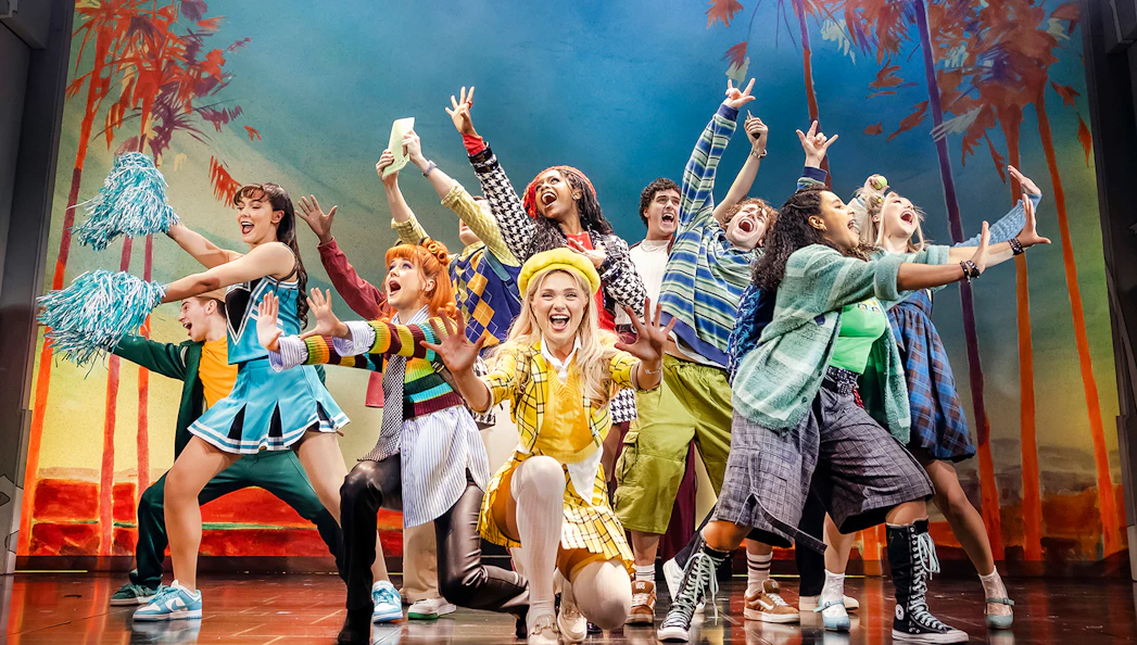 Cast of Clueless The Musical performing energetically on stage with colorful costumes.