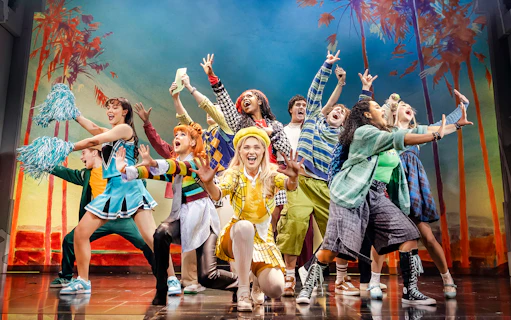 Cast of Clueless The Musical performing energetically on stage with colorful costumes.