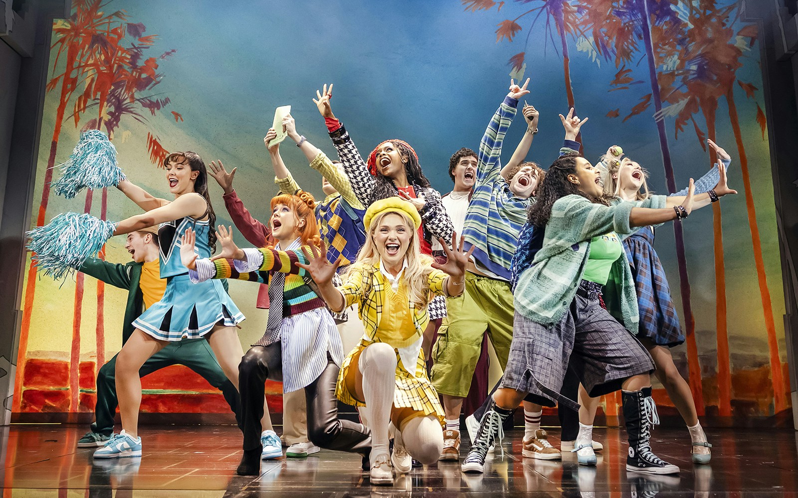 Cast of Clueless The Musical performing energetically on stage with colorful costumes.