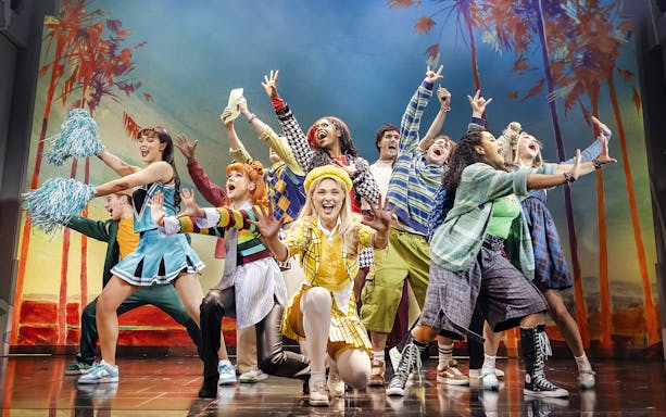 Cast of Clueless The Musical performing energetically on stage with colorful costumes.