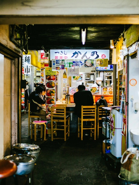 Dining area in Tsukiji Outer Market, Tokyo, with patrons seated at a small eatery.