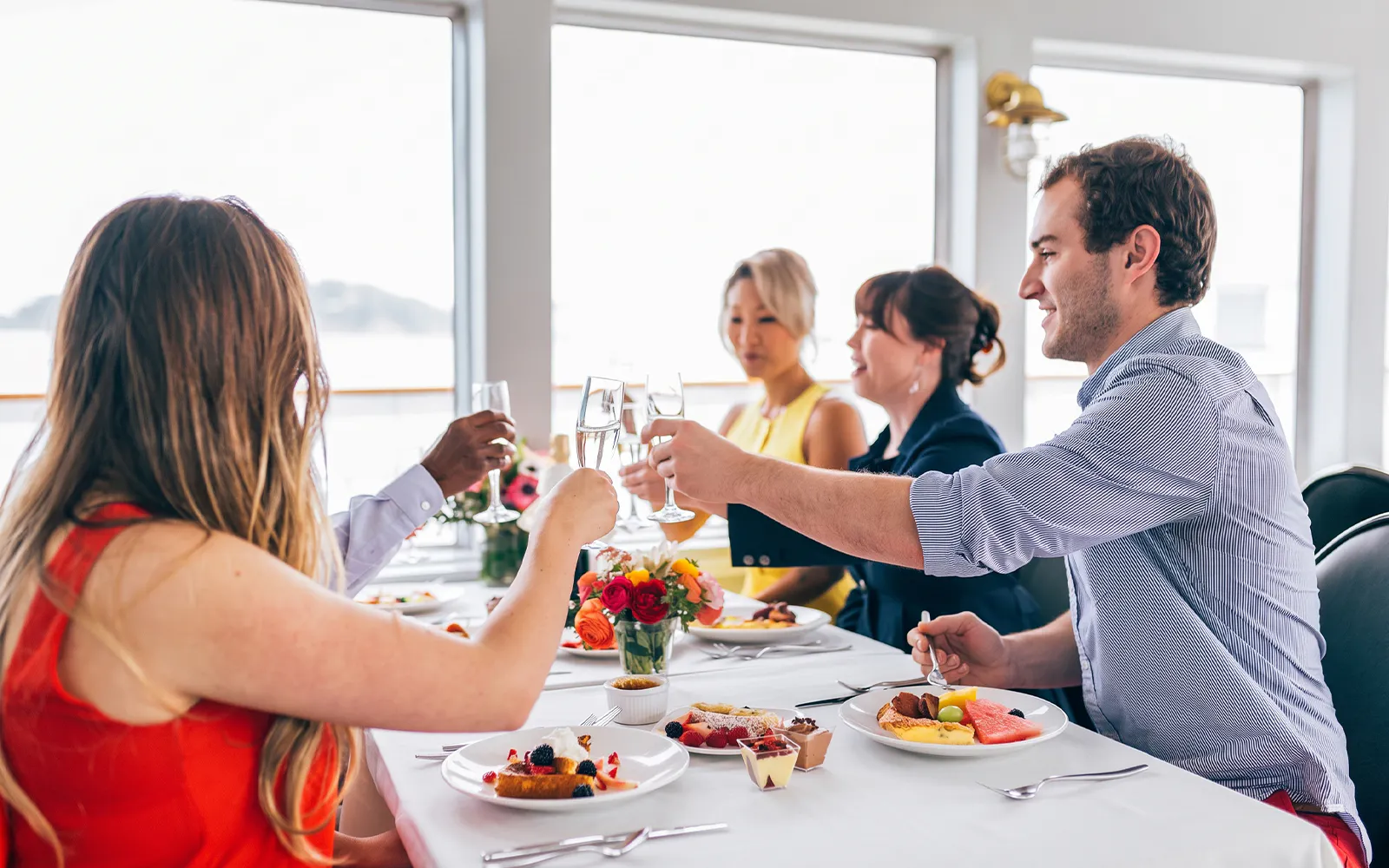 Guests toasting with mimosas at a dining table on Newport Beach brunch cruise.