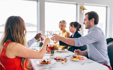 Guests toasting with mimosas at a dining table on Newport Beach brunch cruise.