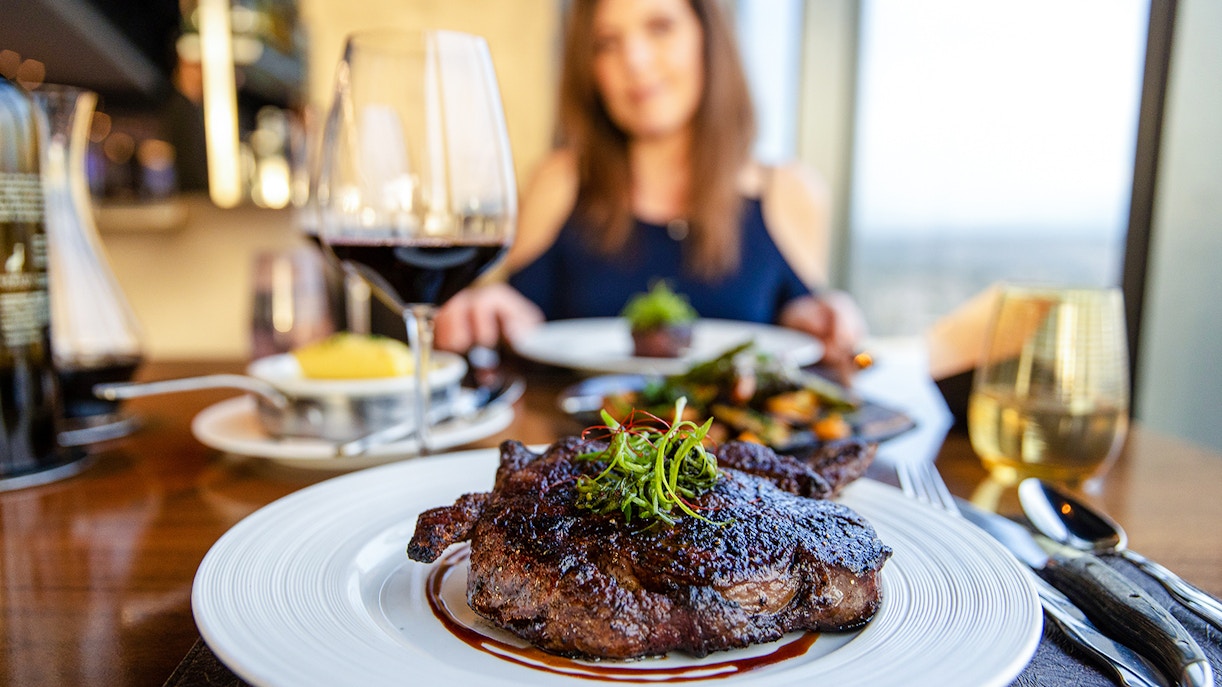 Gourmet ribeye steak with red wine on a dining table.