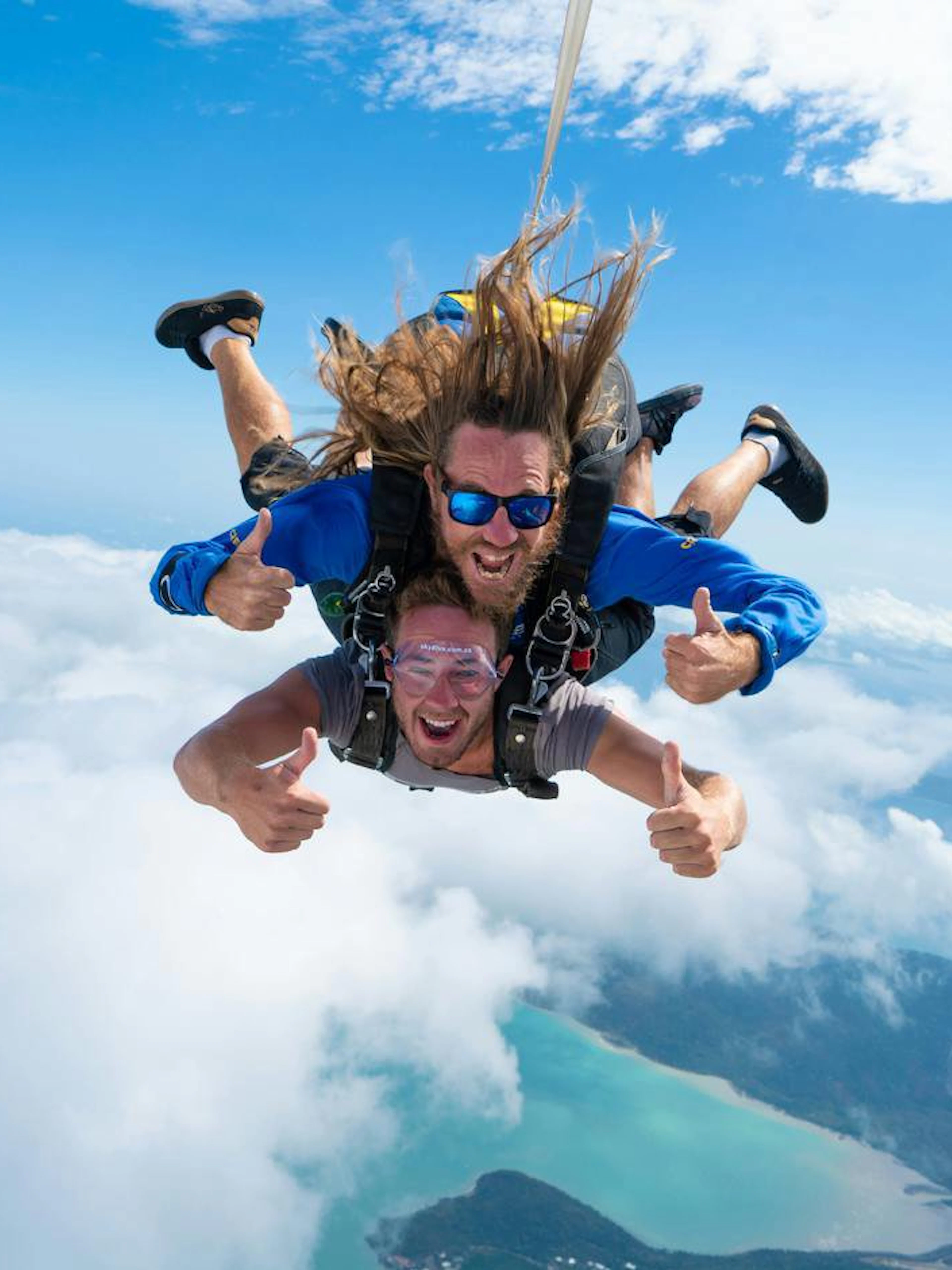 Tandem skydive over Airlie Beach with ocean and islands below.
