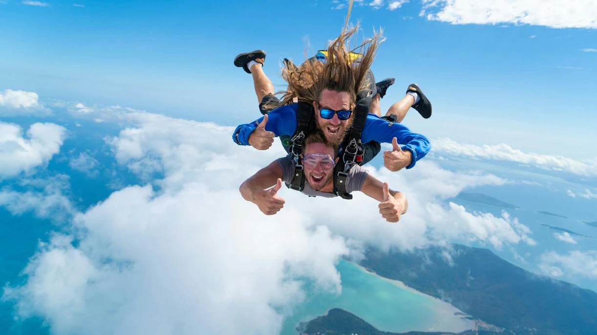 Tandem skydive over Airlie Beach with ocean and islands below.