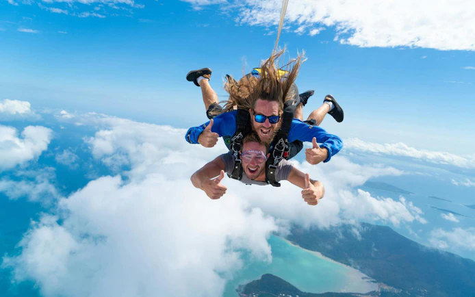 Tandem skydive over Airlie Beach with ocean and islands below.