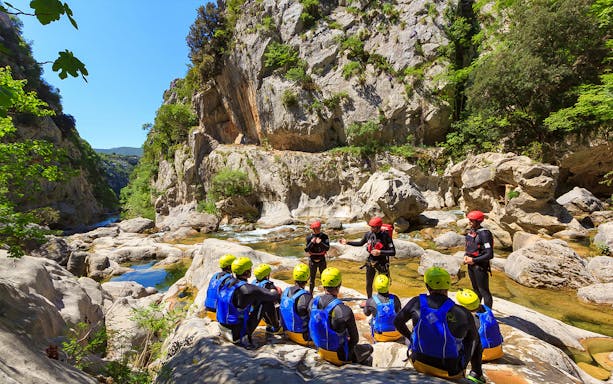 Canyoning group with guides in wetsuits and helmets at Cetina River canyon, Croatia.