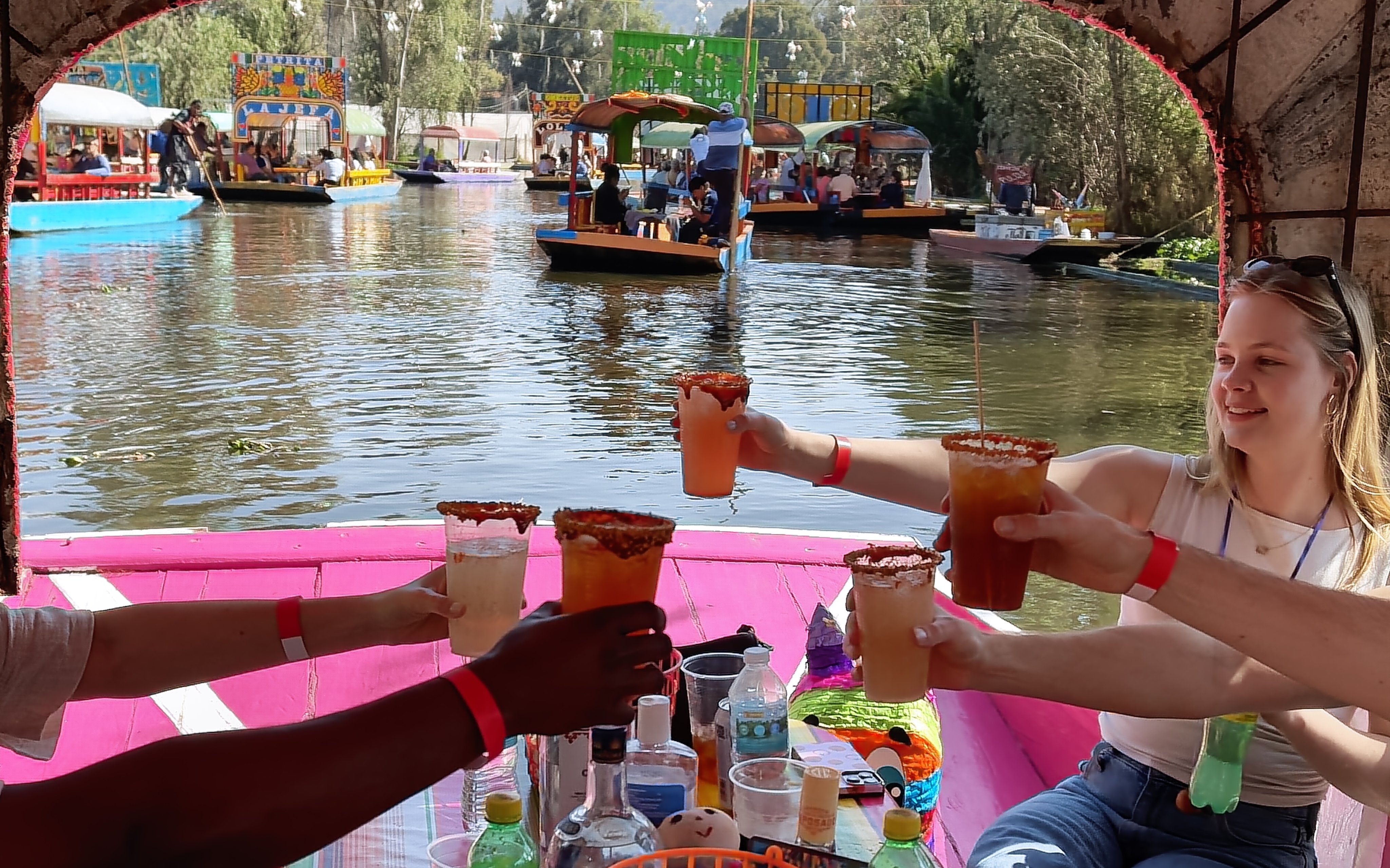 Guests toasting with drinks on a colorful boat in Xochimilco canals, Mexico City.