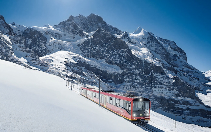 Jungfraubahn train ascending snowy Alps towards Jungfraujoch, Switzerland.