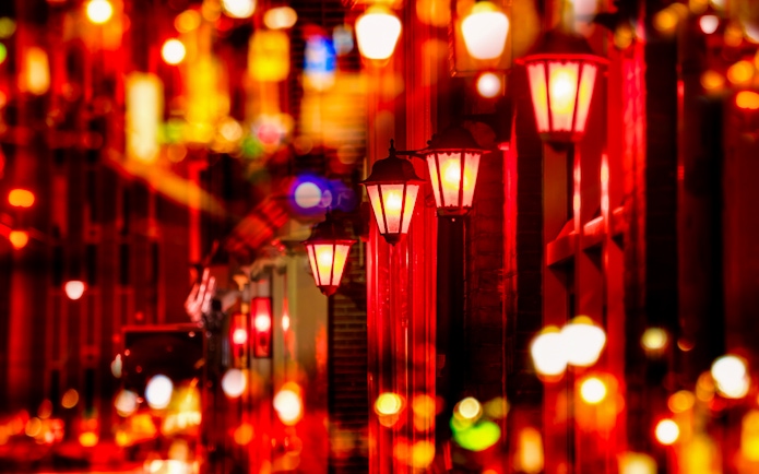 Street lights illuminating the Red Light District in Amsterdam at night.