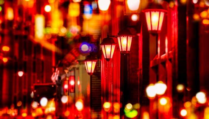 Street lights illuminating the Red Light District in Amsterdam at night.