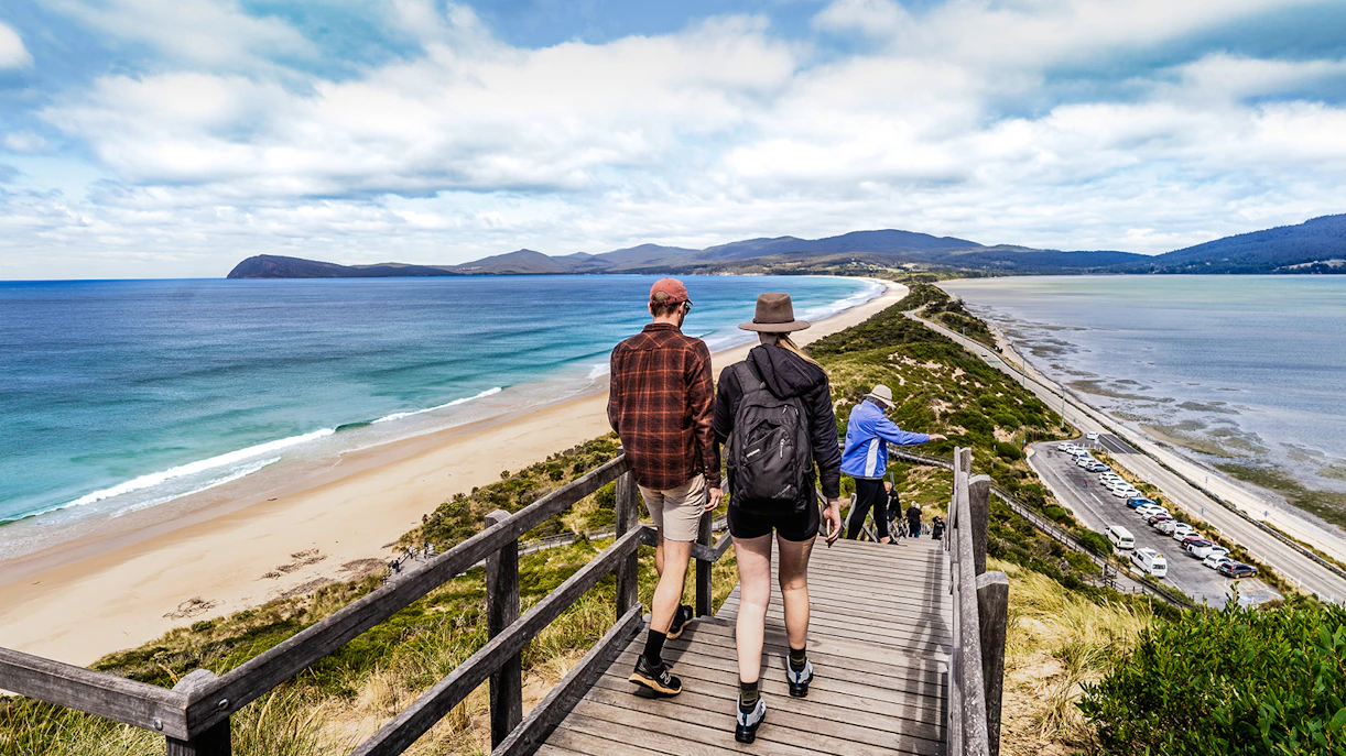 Tour group savoring local cuisine with Bruny Island lighthouse in the background.