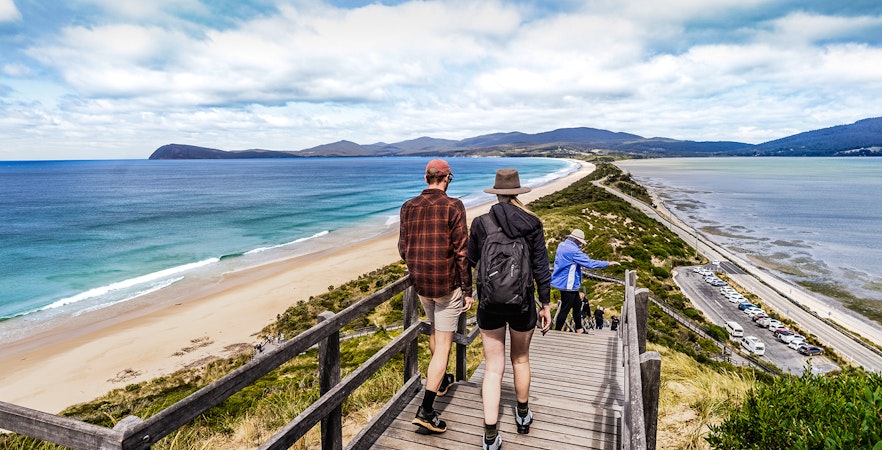 Tour group savoring local cuisine with Bruny Island lighthouse in the background.