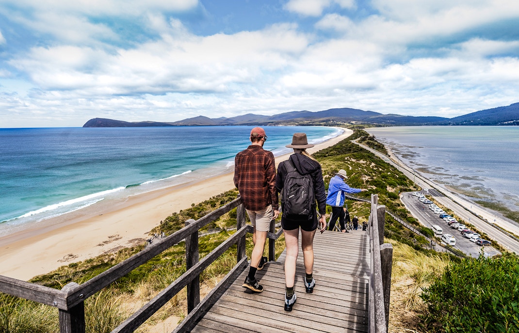 Tour group savoring local cuisine with Bruny Island lighthouse in the background.