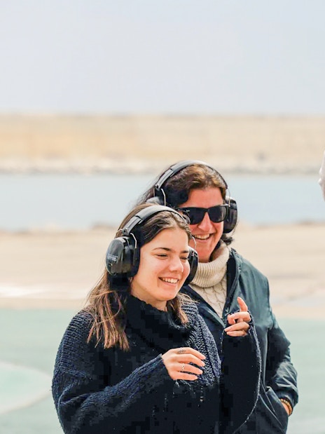 Tourists wearing headphones enjoying an outdoor experience by the water.