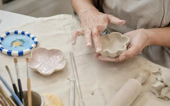 Hands shaping clay into a flower dish at a Krakow air-dry clay workshop.