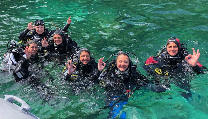 Group of divers in wetsuits enjoying a scuba diving baptism