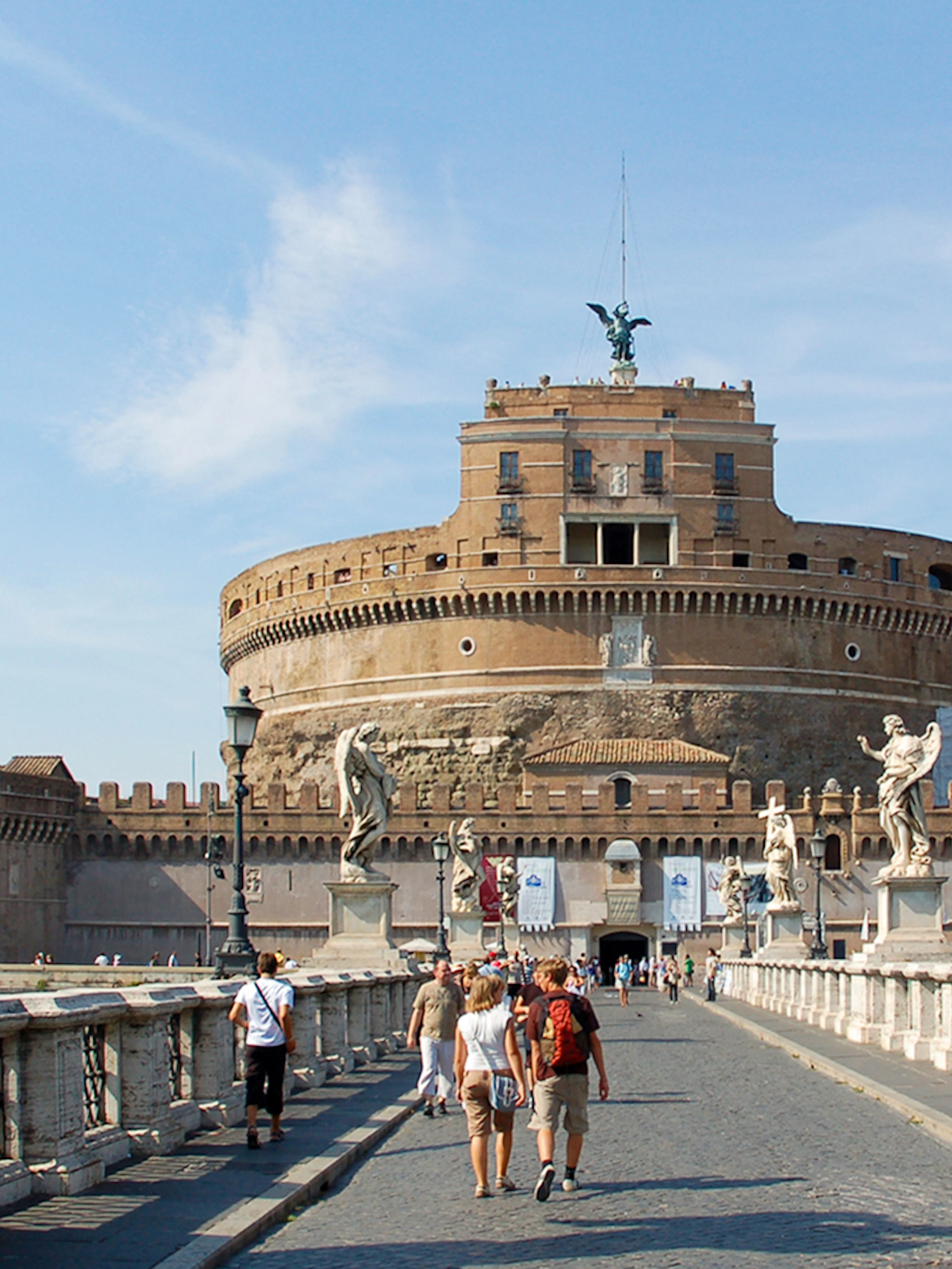 Tour group walking towards Castel Sant'Angelo in Rome, Italy, with historic statues and architecture.