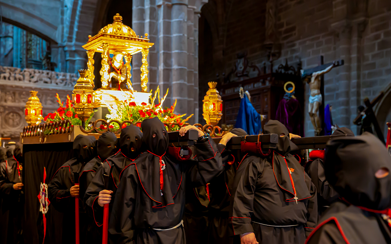 Procession during Semana Santa in Ávila with hooded participants carrying a religious float.