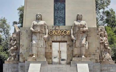 Monument with statues at Obregón site, part of Hidden Gems of Mexico City exploration game.