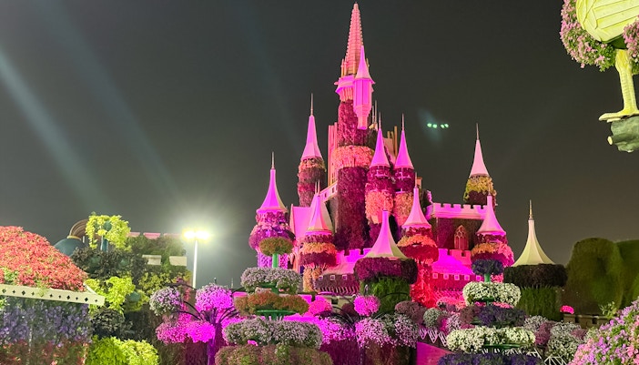 Floral castle display illuminated at night in Dubai Miracle Garden.