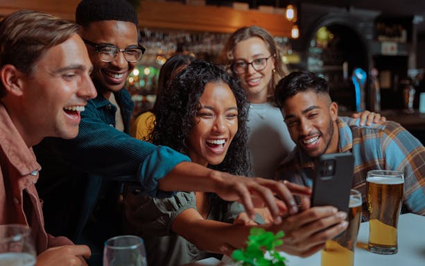 Group enjoying a pub crawl in Rome, taking a selfie with drinks.