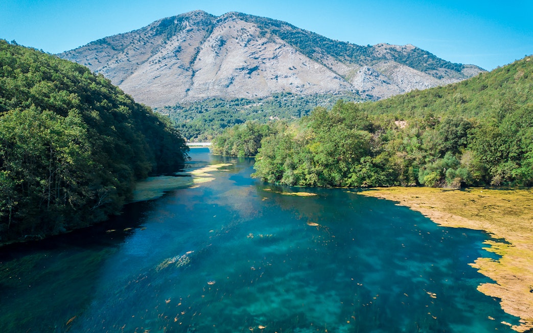 Aerial view of the Blue Eye spring surrounded by lush greenery in Albania.