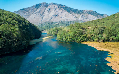 Aerial view of the Blue Eye spring surrounded by lush greenery in Albania.