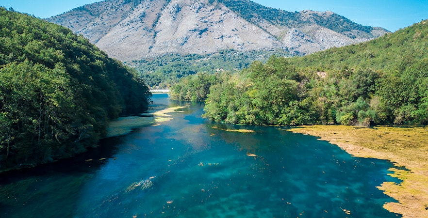 Aerial view of the Blue Eye spring surrounded by lush greenery in Albania.
