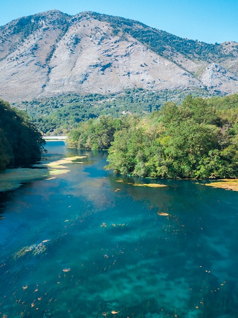 Aerial view of the Blue Eye spring surrounded by lush greenery in Albania.
