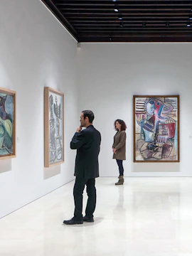 Visitors viewing paintings at Picasso Museum, Malaga on a guided tour.