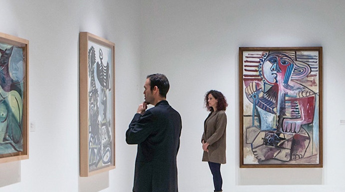 Visitors viewing paintings at Picasso Museum, Malaga on a guided tour.