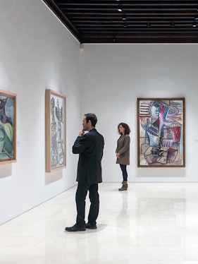 Visitors viewing paintings at Picasso Museum, Malaga on a guided tour.