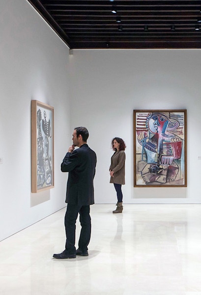 Visitors viewing paintings at Picasso Museum, Malaga on a guided tour.