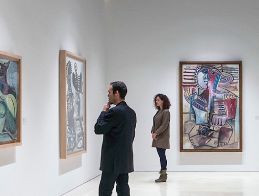 Visitors viewing paintings at Picasso Museum, Malaga on a guided tour.