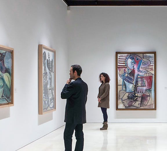 Visitors viewing paintings at Picasso Museum, Malaga on a guided tour.