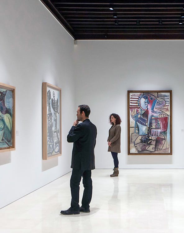 Visitors viewing paintings at Picasso Museum, Malaga on a guided tour.