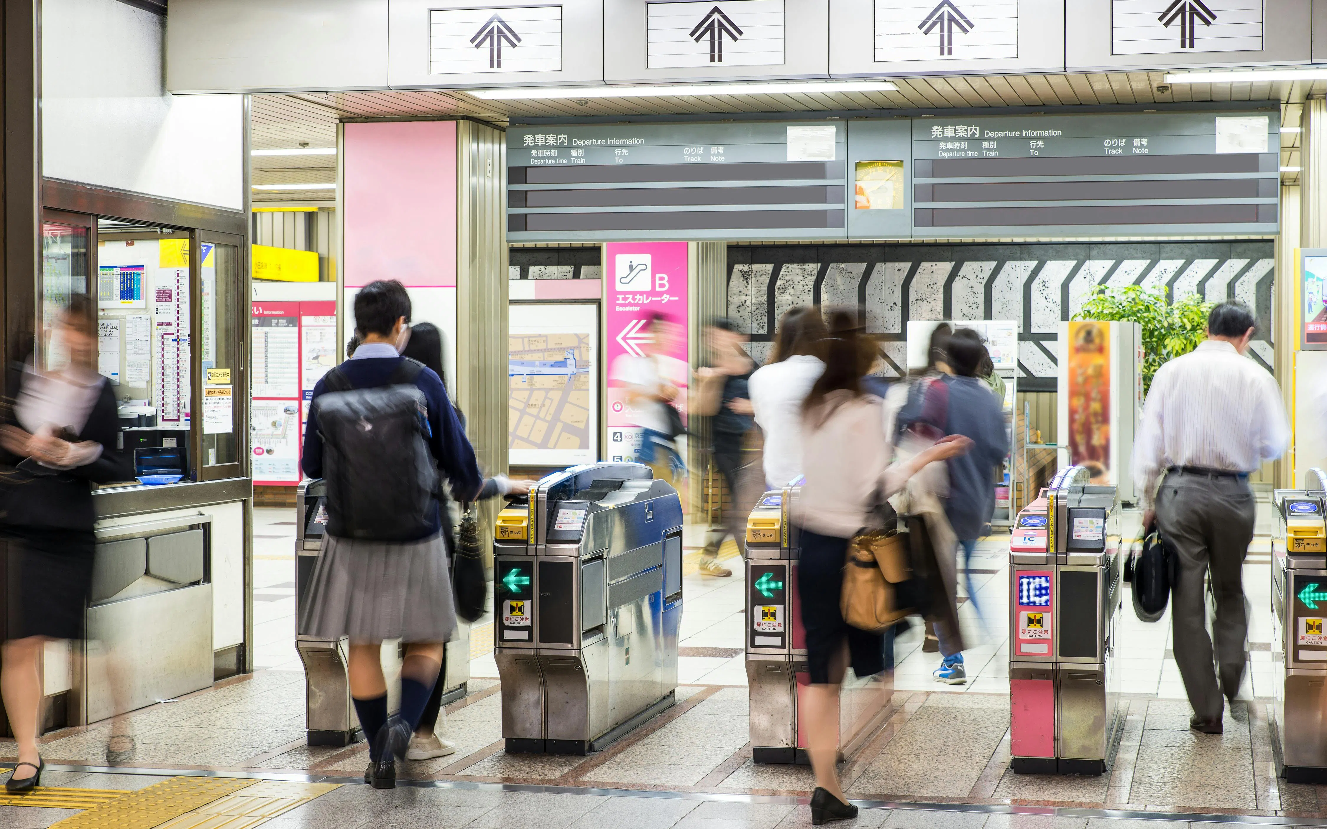 People passing through ticket gates at a busy subway station in Japan.