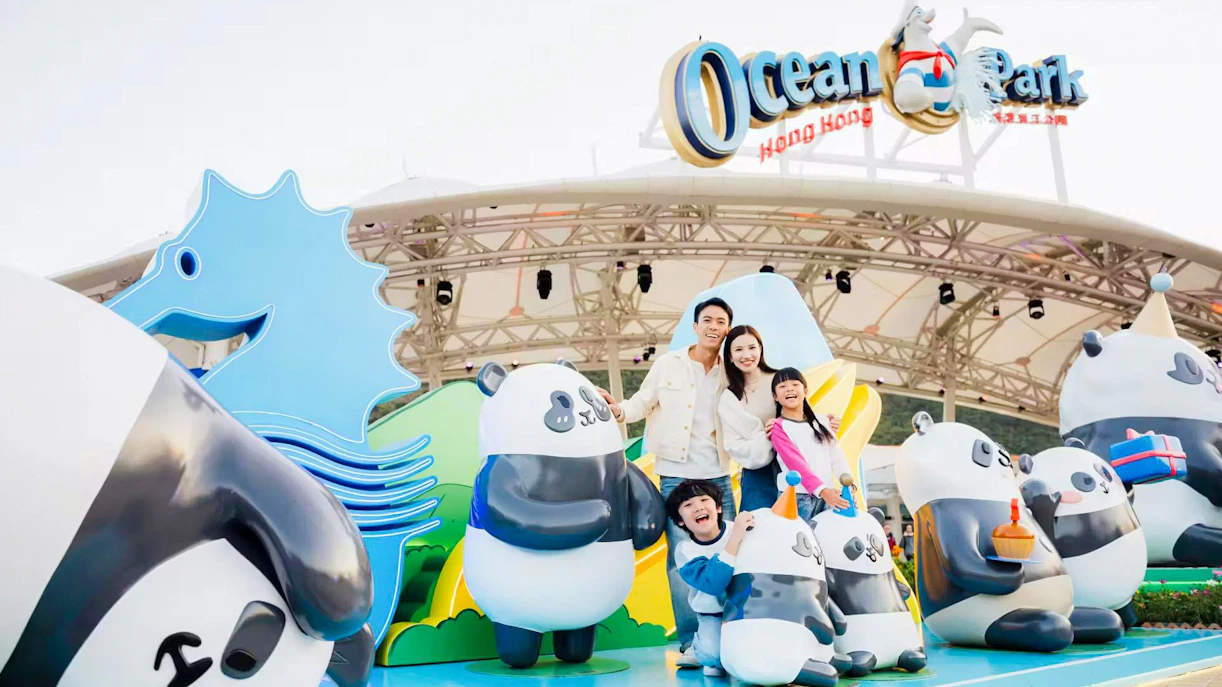 Family posing with panda statues at Ocean Park entrance, Hong Kong.