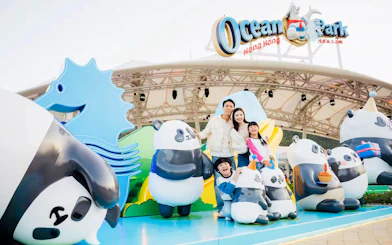 Family posing with panda statues at Ocean Park entrance, Hong Kong.