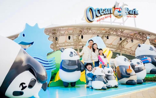 Family posing with panda statues at Ocean Park entrance, Hong Kong.